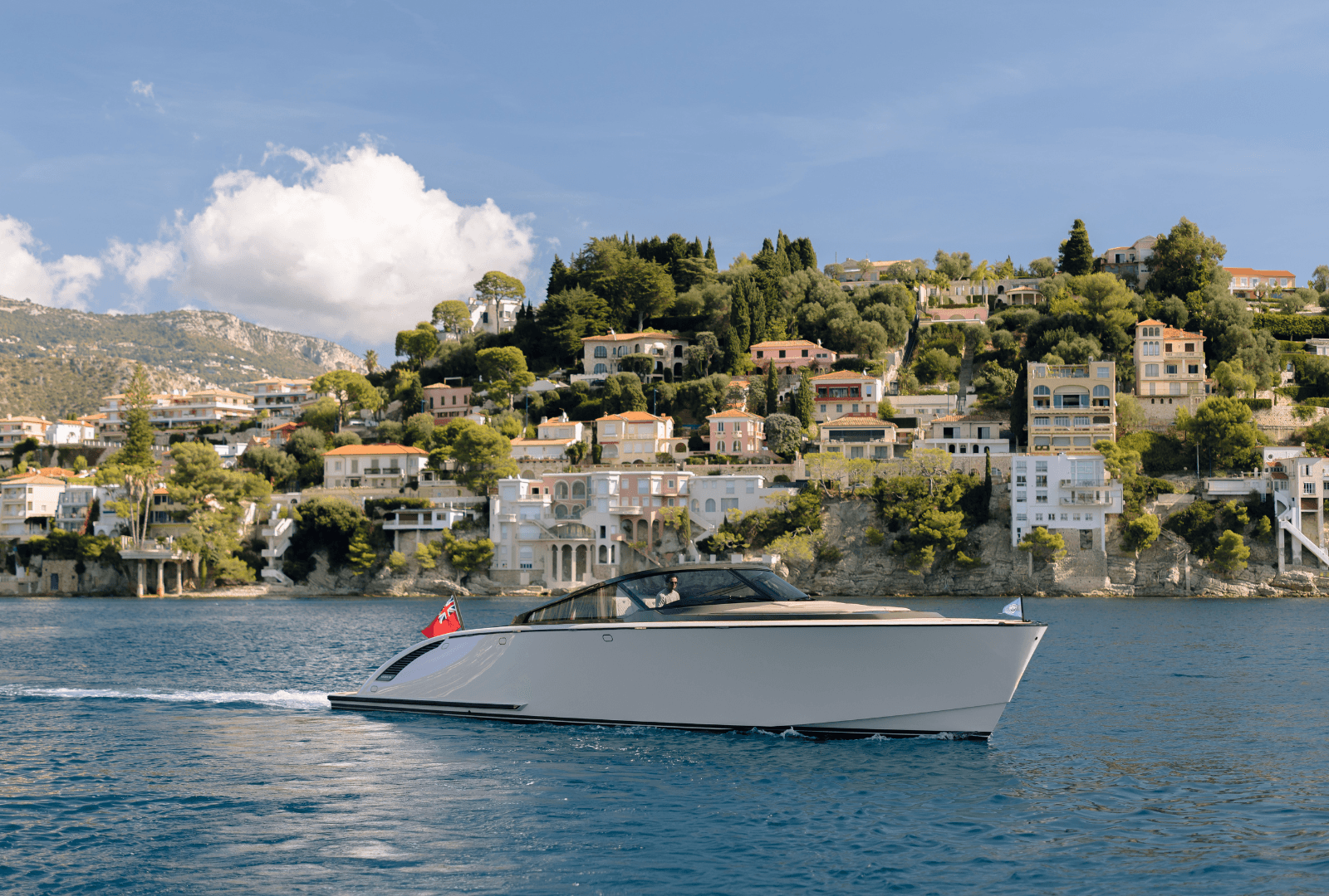 Luxury yacht sailing near a scenic coastal village with hillside houses under a clear blue sky.